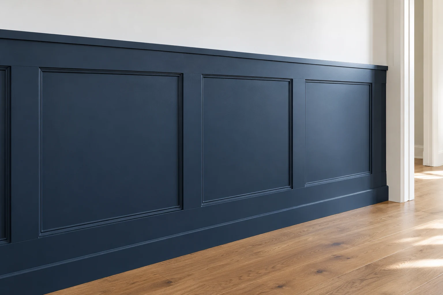 Illustrative finished navy rail-and-stile wainscoting with inset molding, a white wall and an oak floor